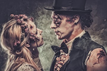 Dressed in wedding clothes romantic zombie couple walking on the abandoned cemetery.