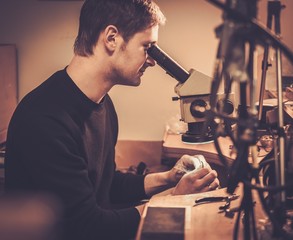 Jeweler looking at the ring through microscope in a workshop.