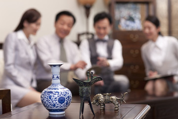 Close up of Chinese antiques with business people in background