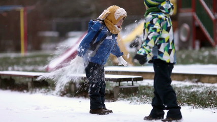 Two boys, brothers, playing in the snow with snowballs, wintertime - Powered by Adobe