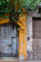 Entrance of yellow old colonial building with wood door and tree 