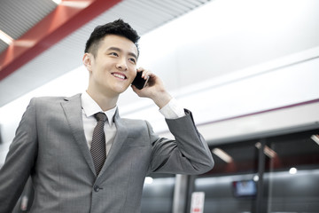 Young businessman on the phone on subway platform