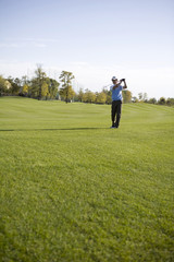Man swinging golf club on golf course