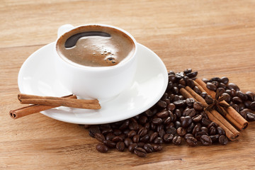 Coffee cup and beans, cinnamon sticks, anise on wooden table