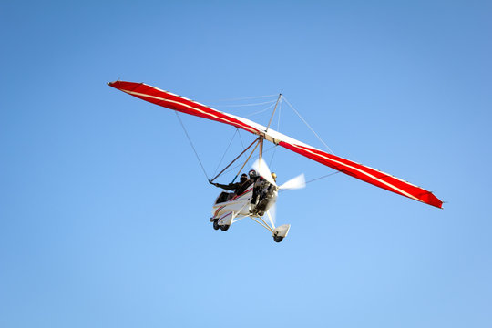 Motorized hang glider soaring in the blue sky
