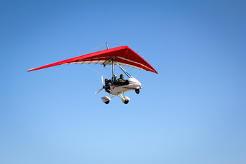 Fototapeta na wymiar Motorized hang glider soaring in the blue sky
