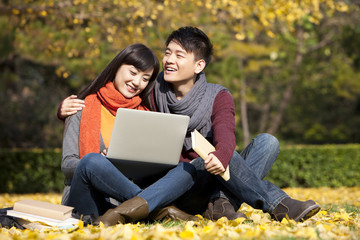 Sweet college couple with laptop and books enjoying the scenic autumn on campus