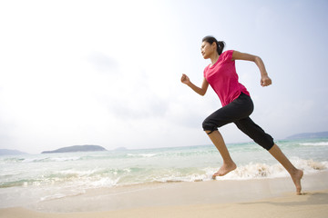 Fototapeta na wymiar Young woman running on the beach