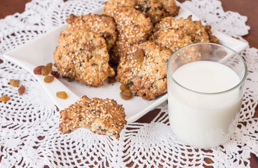 Oat biscuits and a glass of milk. Homemade cereal biscuits with the addition of sesame and raisins.