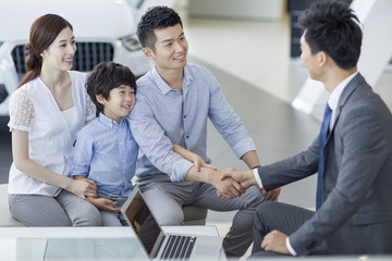 Young family buying car in showroom