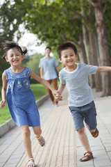 Happy brother and sister holding hands running