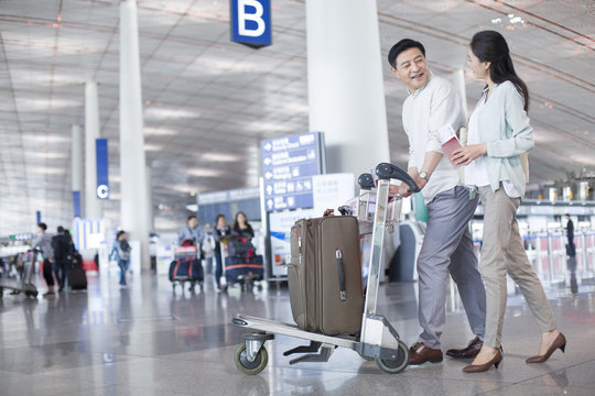 Mature couple walking in airport with suitcase