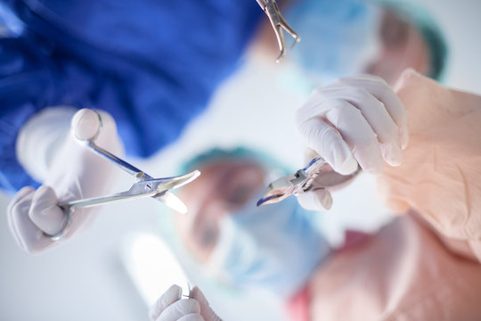 Surgeons holding surgical instrument while operating patient