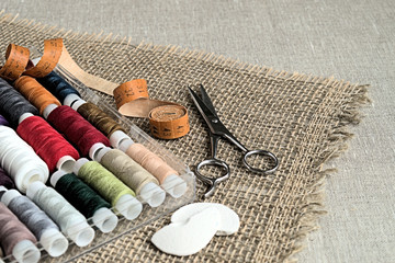 
  Sewing accessories.  Set of multi colored sewing thread, scissors and measuring tape on a...