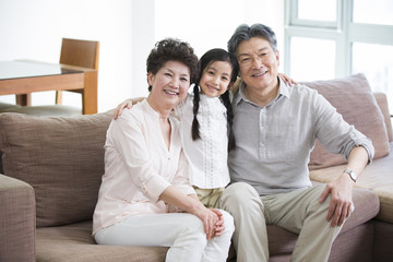 Obraz premium Happy girl with grandparents in living room