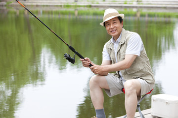 Old man fishing by a pond