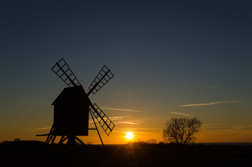 Fototapeta na wymiar Sunset with silhouette of an old windmill