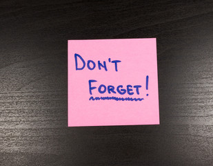 Sticky note with text Don't forget on it, isolated on wooden background