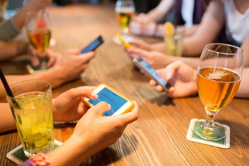 close up of hands with smartphones at restaurant