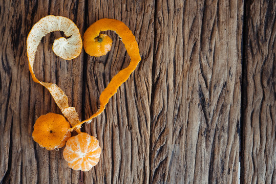 Heart with orange peel on wooden background.