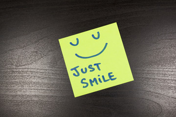 just smile sticky note on wooden background