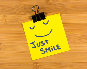 just smile sticky note on wooden background