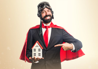 Super hero businessman holding a little house