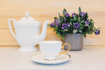 Cup of tea with teapot on wood background.