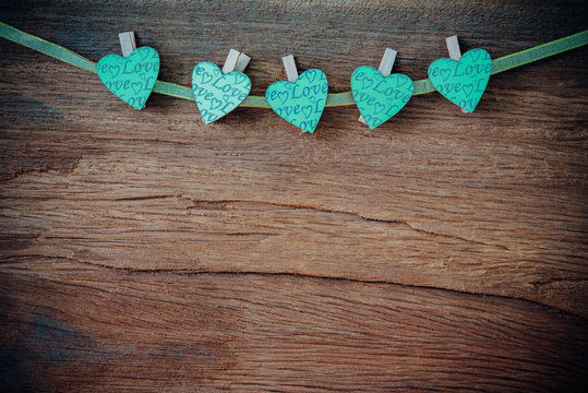Green heart on wooden background.