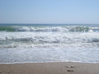 Sparkling foamy waves moving towards beach in sunny summer day