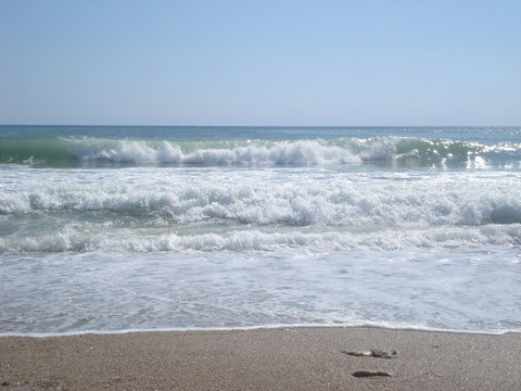 Fototapeta Sparkling foamy waves moving towards beach in sunny summer day