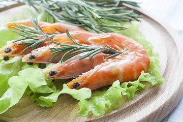 Tiger Prawn Shrimps with green lettuce and rosemary. Prawn Shrimps with green lettuce and rosemary on wooden board.