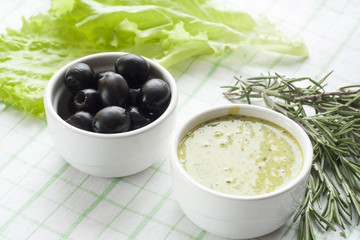 Homemade sauce mayonnaise and marinated black olive and  in ceramic pots with parsley, rosemary, olive oil and fresh tomatoes.
