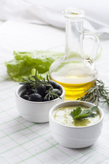 Homemade sauce mayonnaise and marinated black olive and  in ceramic pots with parsley, rosemary, olive oil and fresh tomatoes.