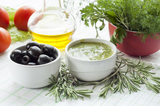 Marinated black olive and homemade sauce mayonnaise in ceramic pots. Marinated black olive and homemade sauce mayonnaise in ceramic pots with parsley, rosemary and fresh tomatoes.