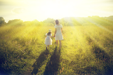 Mother and daughter walking on the meadow.