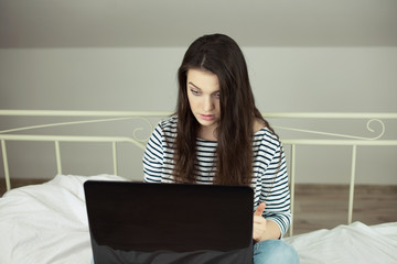 Young girl sitting in bed with laptop