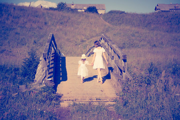 Mother and daughter walking on the meadow.
