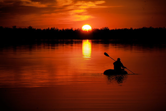 Man In Kayaking On Lake At Sunset