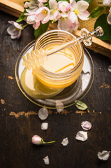Fresh honey in jar with flowers and honeycomb on wooden background