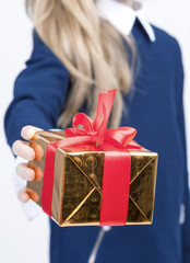 Closeup of Hand of Little Blond Girl Giving Christmas Gift Box Forward