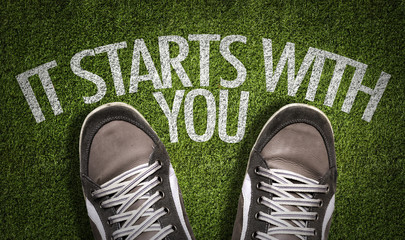 Top View of Sneakers on the grass with the text: It Starts With You