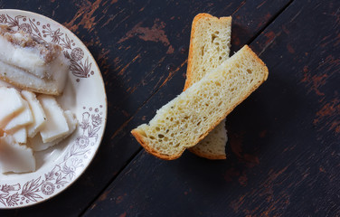 The plate of salted pork fat and sliced bread. Closeup, top view. rustic style