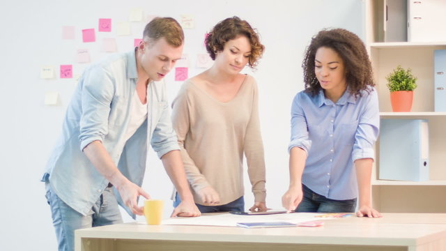 Three coworkers are working with construction drawing. 