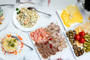 sliced sausages, pickles and salads on banquet table