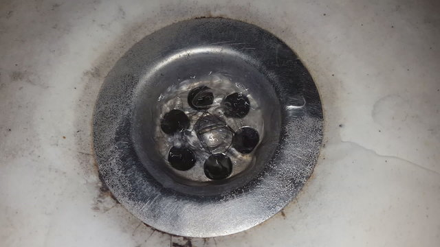 Old dirty wash basin, water running down the drain.