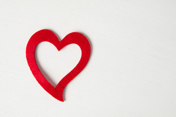 single red felt heart on a white painted wood background