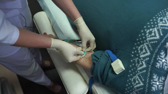 The doctor takes blood from a vein