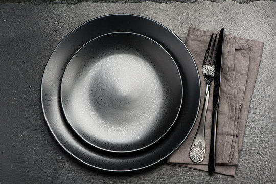 Black plate with fork and knife on Black stone background