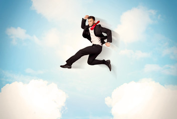 Business person jumping over clouds in the sky